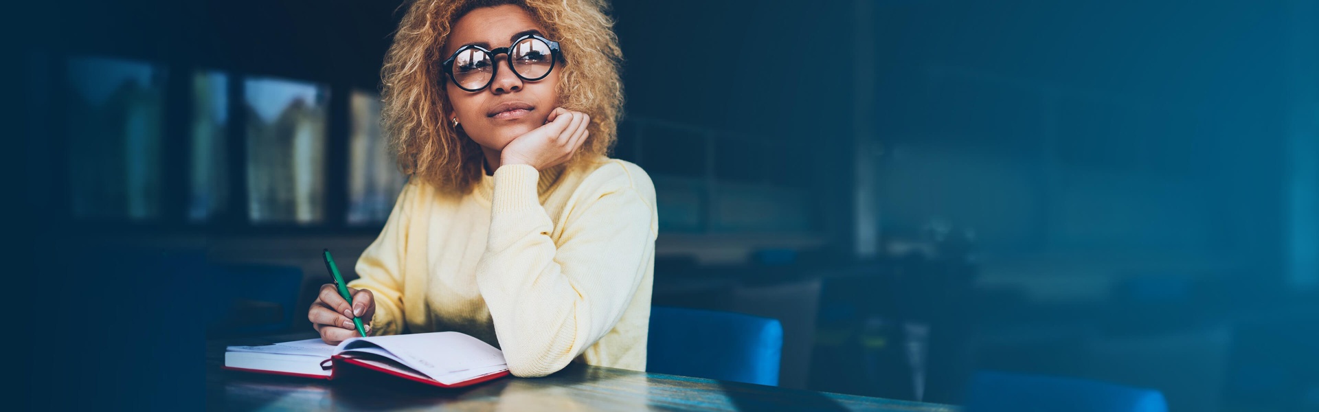 A woman with glasses studying at a table.